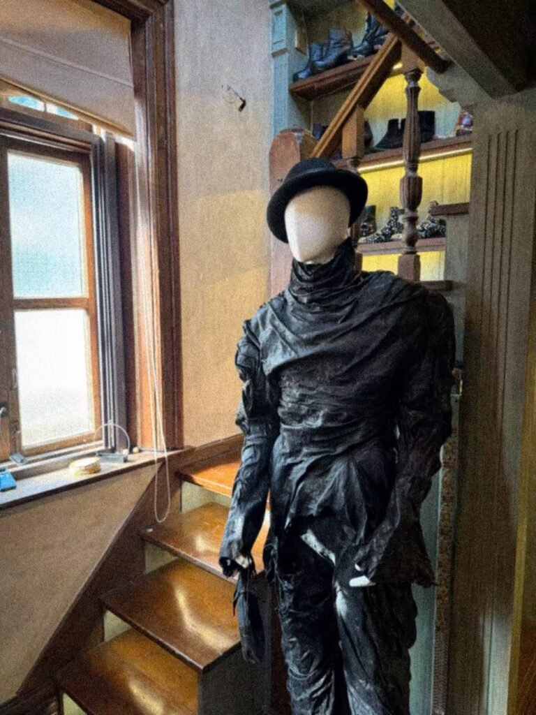 Black sculptural outfit on a mannequin beside the wooden staircase at SECTION.