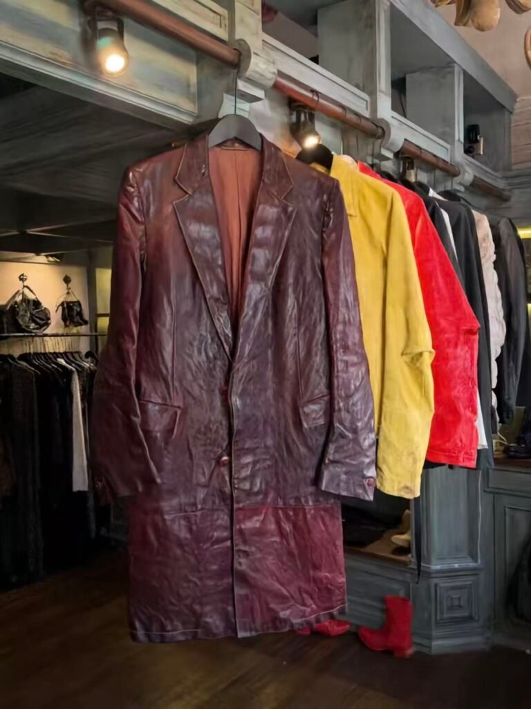A burgundy leather jacket with coloured garments on the rail.